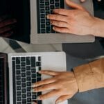 Two individuals working collaboratively on laptops, showcasing teamwork and modern technology.