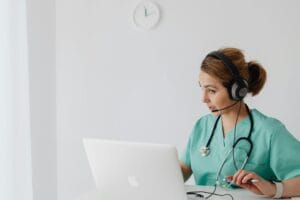 Medical professional using laptop and headphones for an online consultation in a modern office.