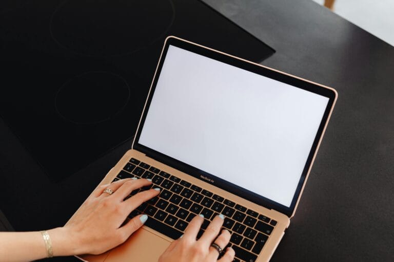 Hands typing on a laptop with a blank screen, perfect for mockup or design presentations.