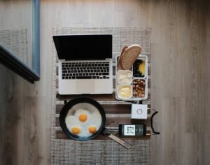 photo of MacBook Pro, frying pan with eggs and bread on gray mat