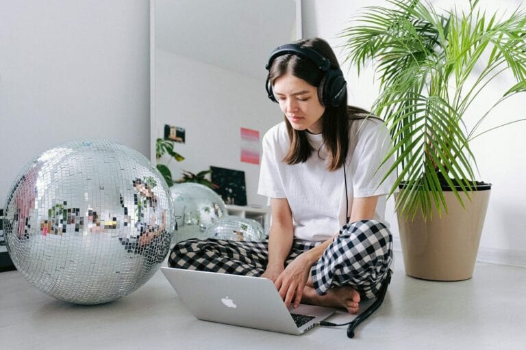 A Woman In A Cozy Setting With Headphones And Laptop, Embodying Remote Work Lifestyle.