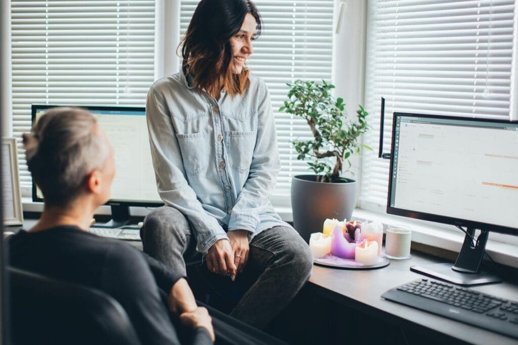 A Smiling Couple Converses In A Cozy Home Office With Candles And Computers.