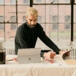 a man sitting at a table working on a laptop