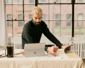 A Man Sitting At A Table Working On A Laptop