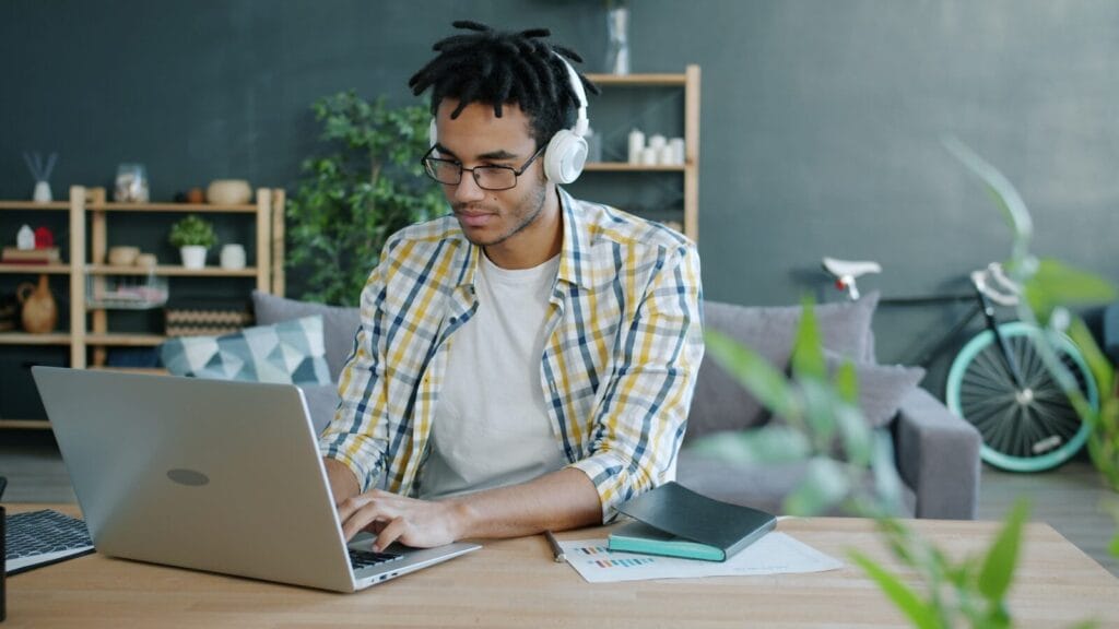 Man With Headphones Working On Laptop At Home Office.