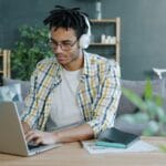 Man with headphones working on laptop at home office.