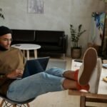 Casually dressed man freelancing with laptop in stylish, plant-filled home office.