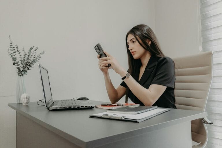 A Woman Using Her Phone At A Desk