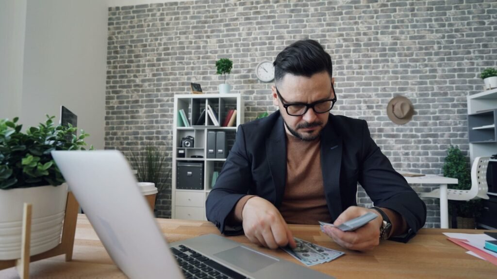 A Man Sitting At A Table In Front Of A Laptop