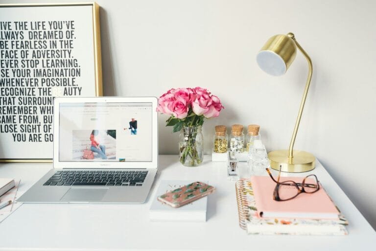 Macbook Air Beside Gold-Colored Study Lamp And Spiral Books