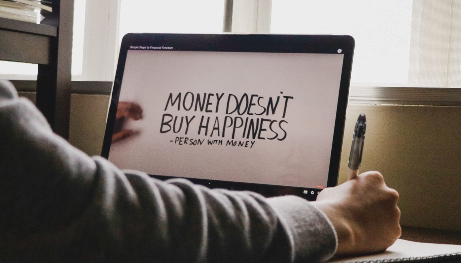 a person writing on a computer screen with a pen